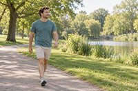 An adult man takes a relaxed walk through a green park as part of everyday physical activity.